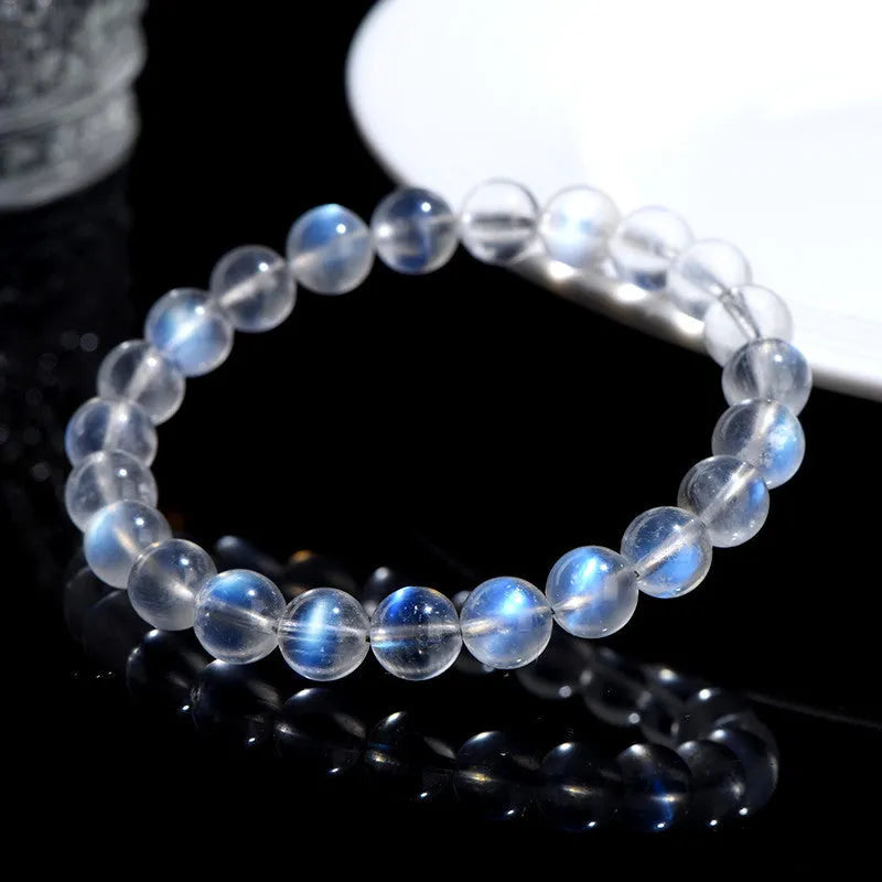 Polished natural cream body blue moonlight crystal bracelet on a wrist, showing simple bead design.