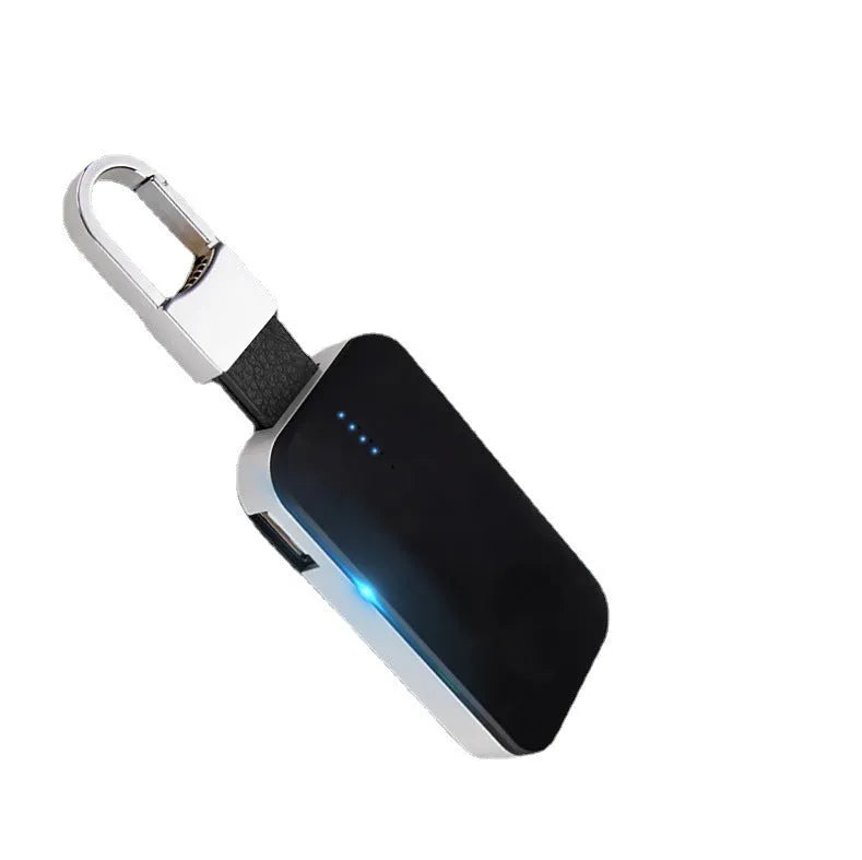 Black Apple Watch keychain power bank with wireless charging pad next to an Apple Watch.