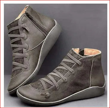 Women's black casual ankle boots with a round toe and a low wedge heel on a wooden floor.