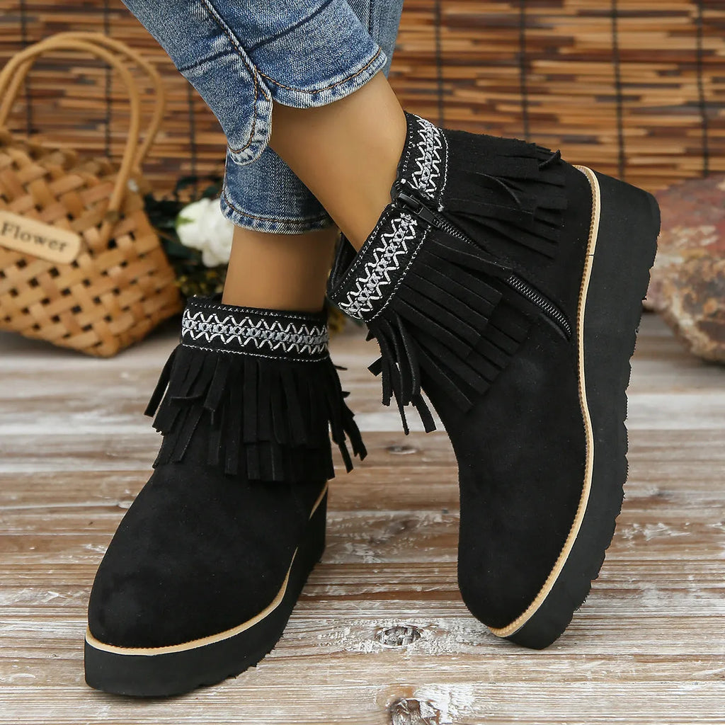 Women's suede wedge ankle boots with a thick platform sole, side zip, and tassel detail in dark brown.