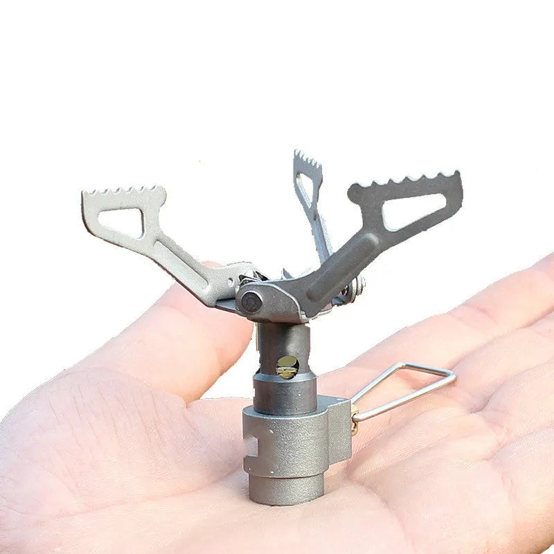 Compact one-piece propane camping stove on a rocky outdoor surface.