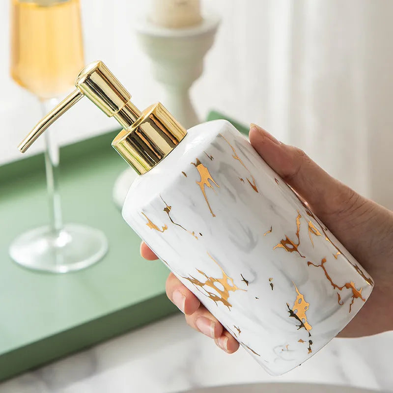 White ceramic bathroom wash kit set with two cups, a soap dish, and a bottle on a marble background.