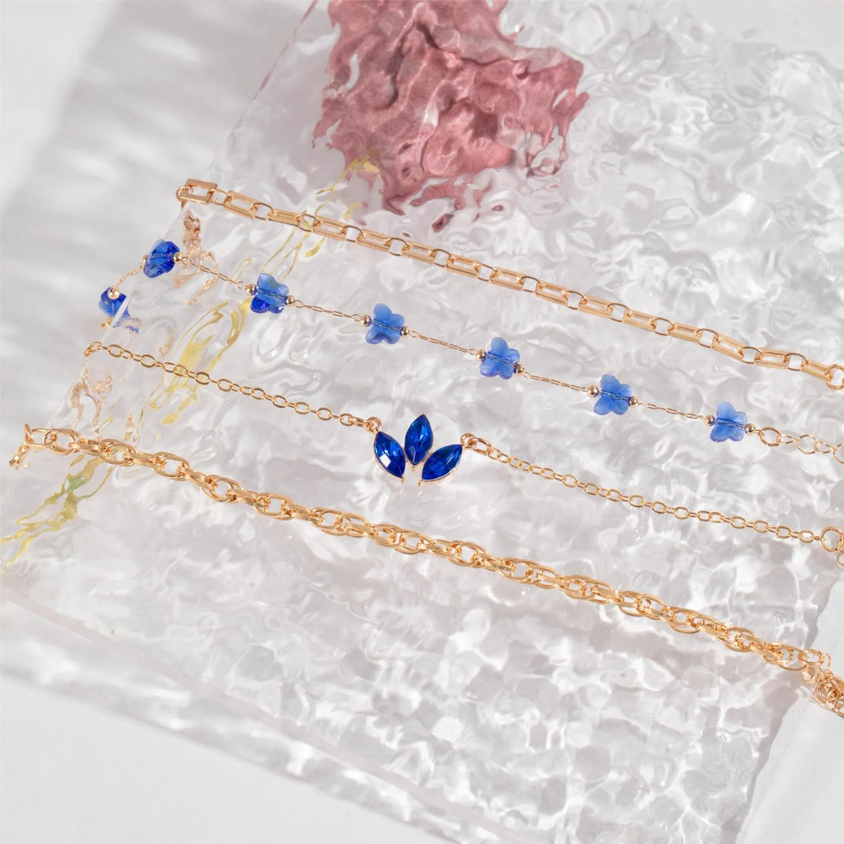 Four-piece blue and gold-tone bracelet set with heart, butterfly, and flower designs, rhinestone accents, alloy electroplated finish