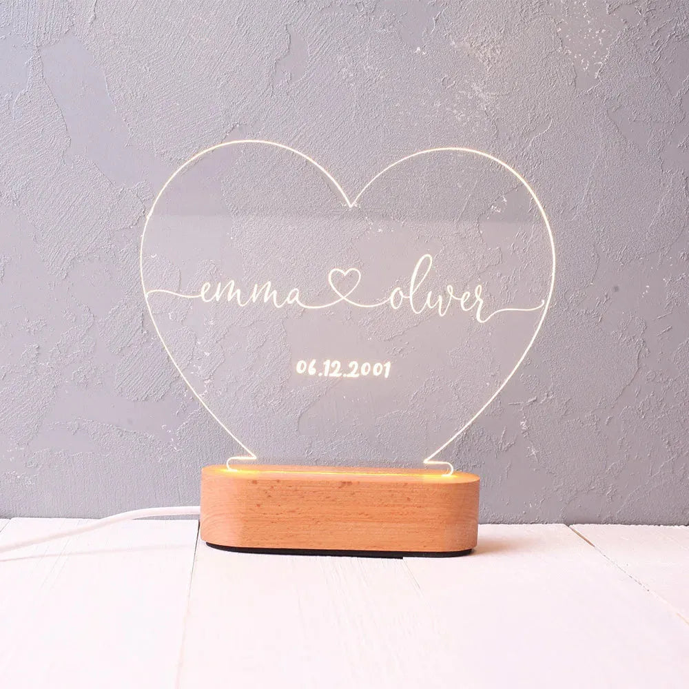 Custom clear acrylic night light displaying personalised names and date, lit by an LED base.