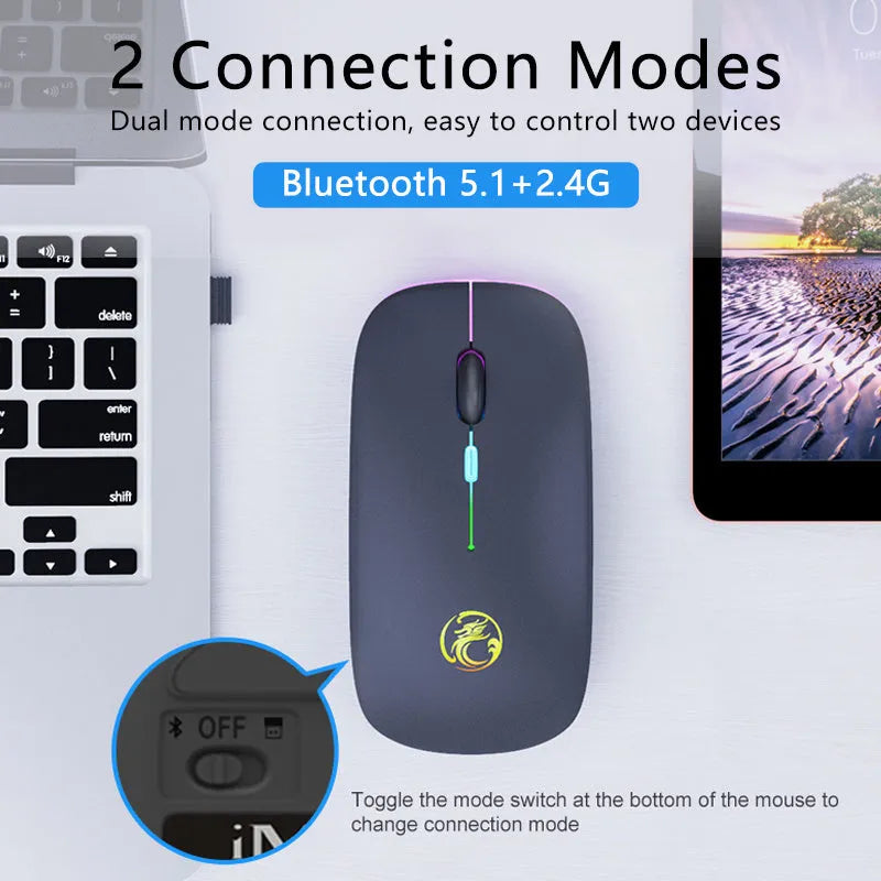 White dual-mode wireless mouse with silent buttons on a wooden desk next to a laptop.