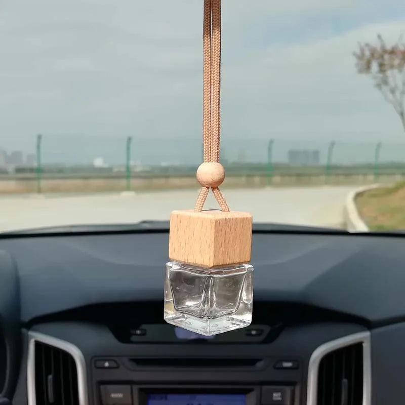 Square clear glass car fragrance pendant bottle with 8ml capacity hanging from a rearview mirror