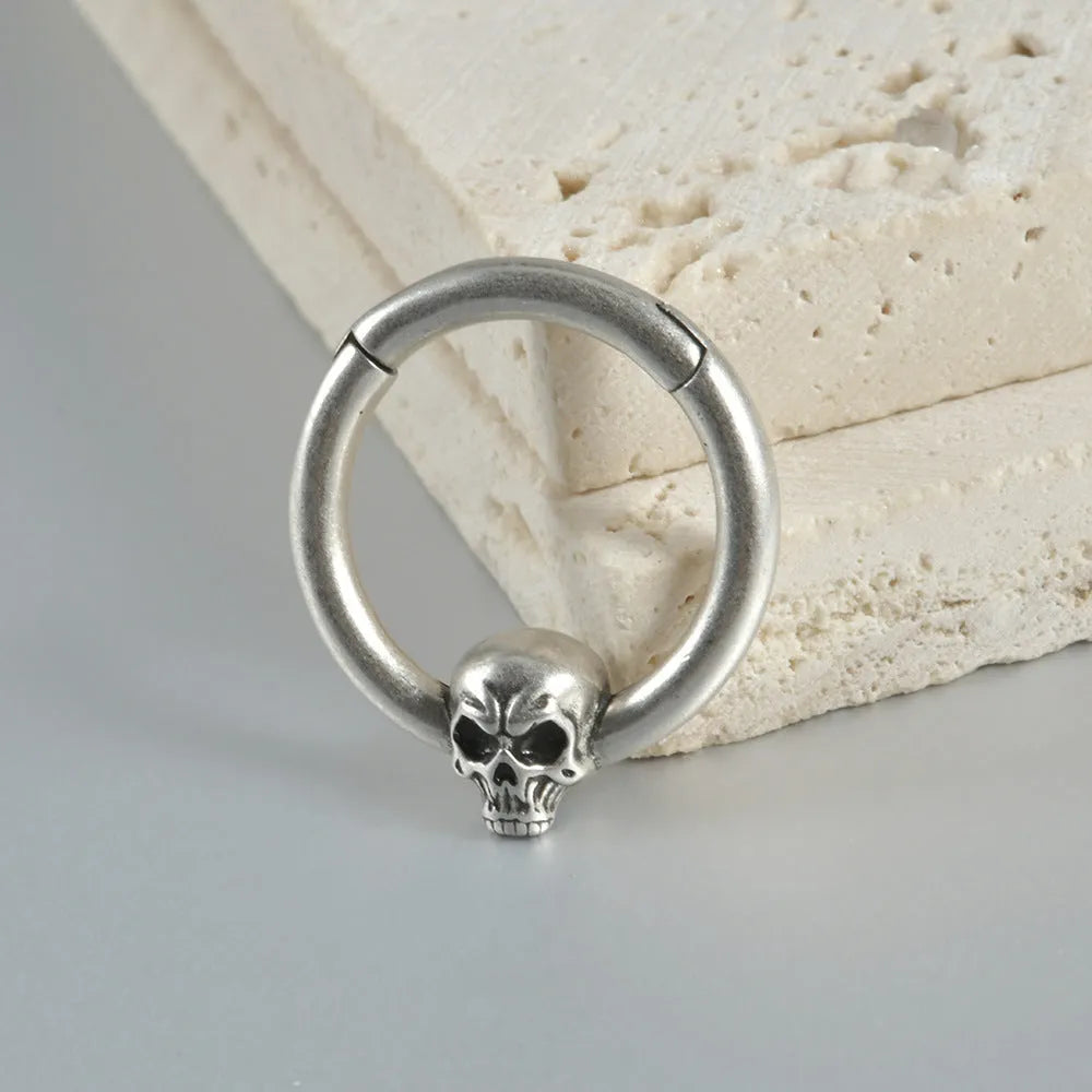 A pair of vintage-style copper earrings with an embossed ghost head design on a stud post, showing an antique silver finish.
