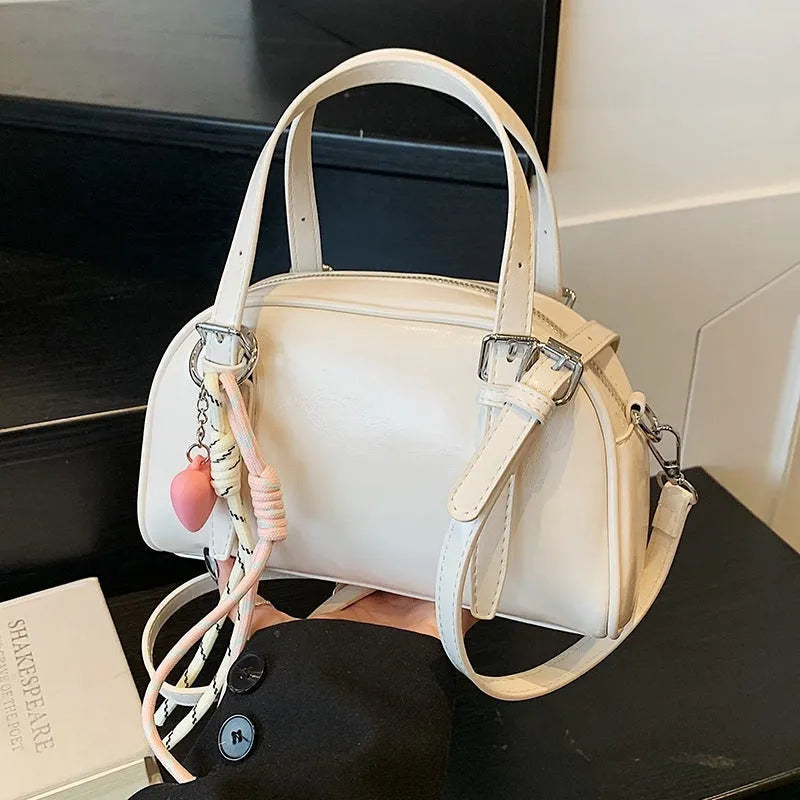 Soft PU women's shoulder bag in shell shape with sandwich pocket, shown in black with pendant strap.
