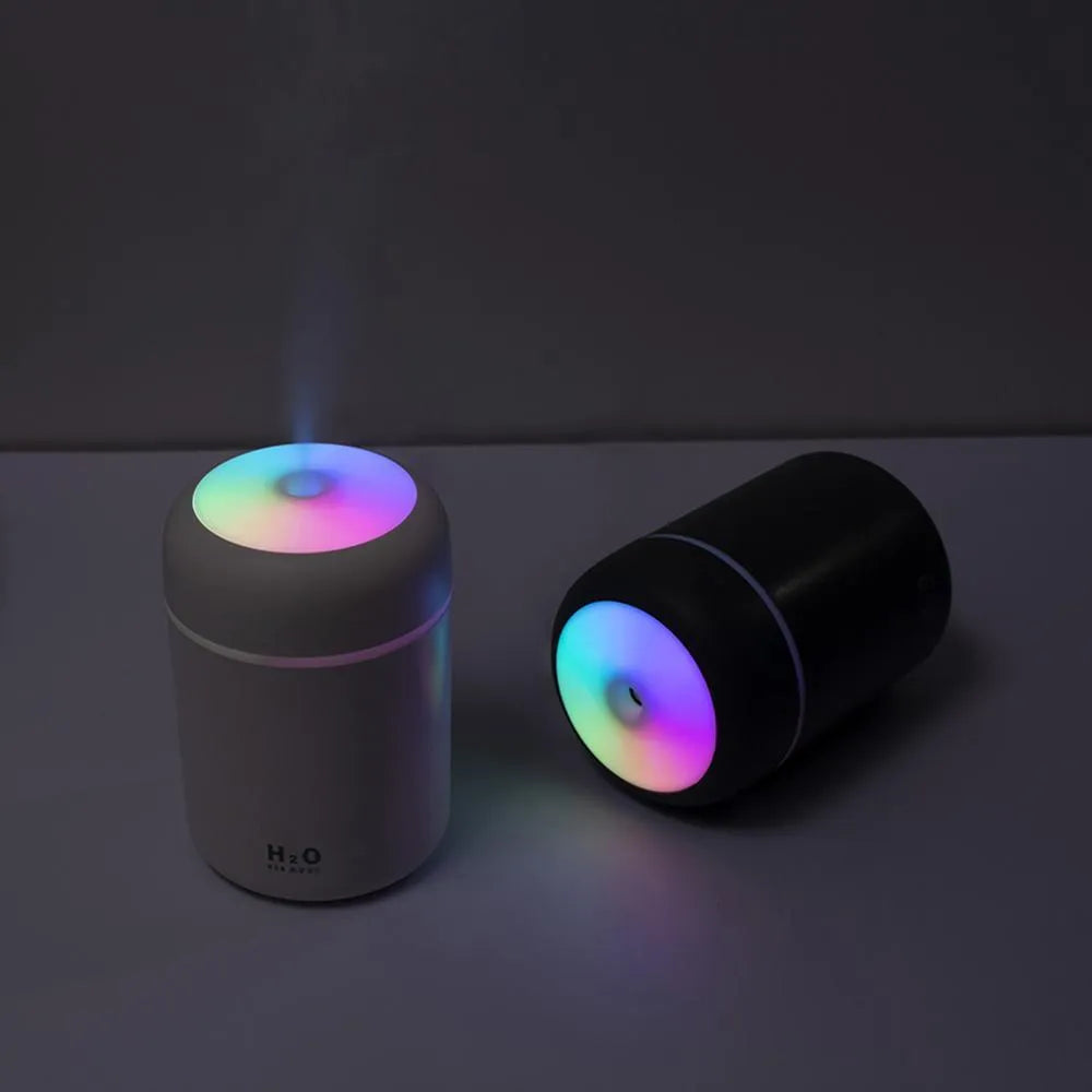 Pink USB desktop humidifier with LED lights and water tank on wooden desk