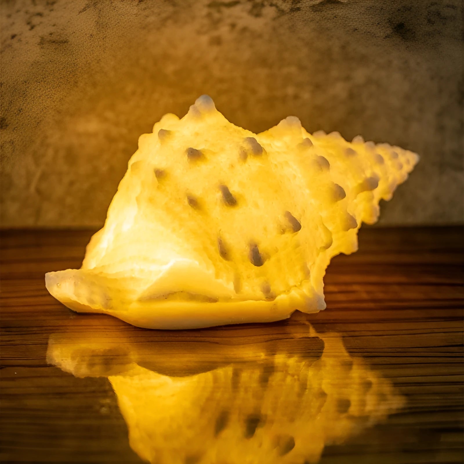 Small geometric night lamp with built-in battery in conch colour, dimensions 13 by 19 by 11 cm, on a bedside table