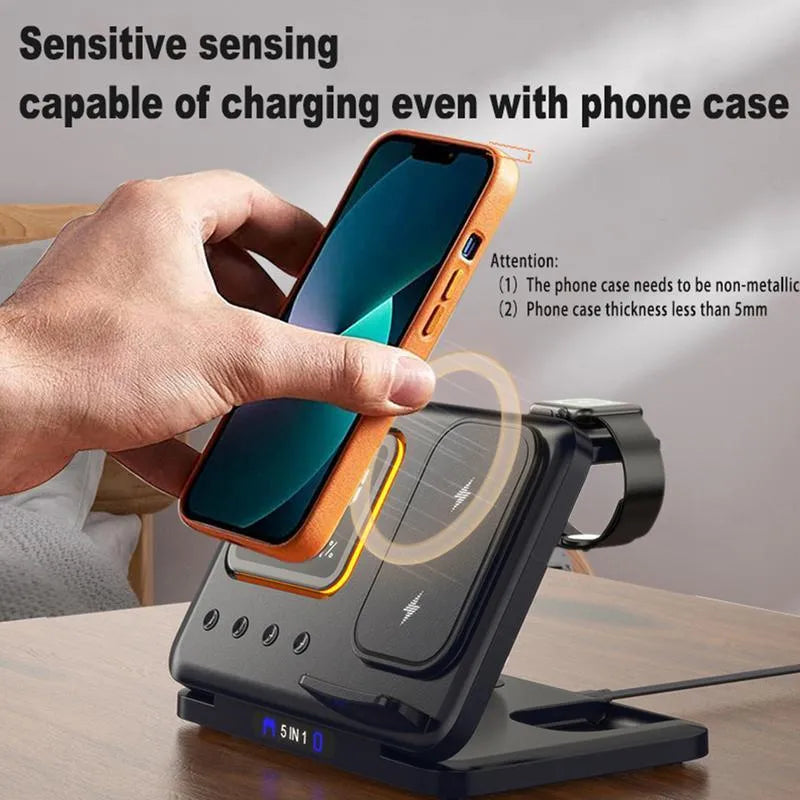 Black 5-in-1 wireless charging station displaying time and temperature, charging a phone and a smartwatch.