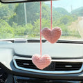 Green and white crocheted wool car plant decoration with a white hanging rope.