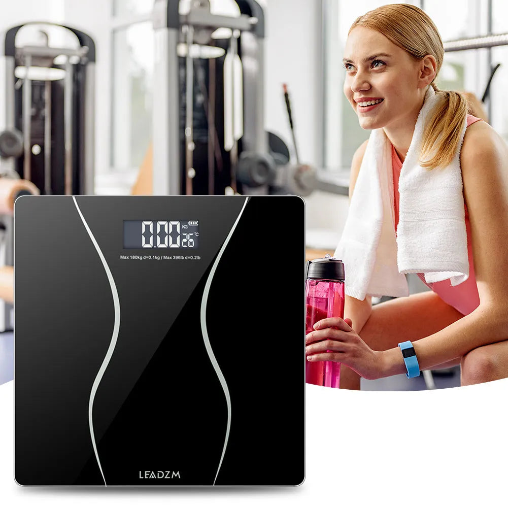 Black electronic digital bathroom scale on a floor showing a maximum capacity of 180 kg.