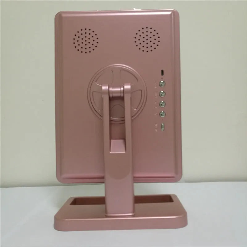 Pink touch screen LED makeup mirror with Bluetooth speaker and magnifying mirror on a table.