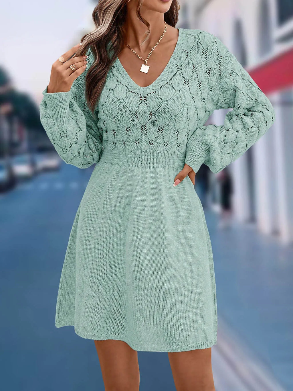 A high-waisted, long-sleeve v-neck dress with a 3D pattern in a light blue green colour.