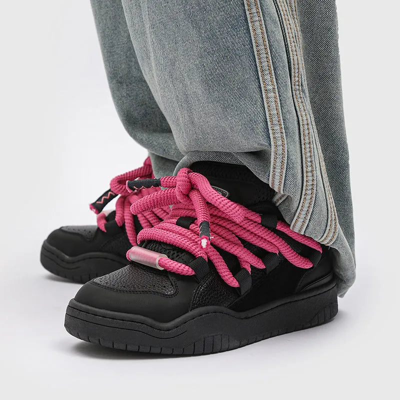 Pair of low-top unisex casual sneakers with thick flat rubber sole and lace-up front in a solid colour.