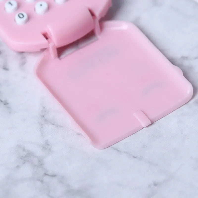 Creative cookie-shaped cute mini calculator in pink with key ring on a white background