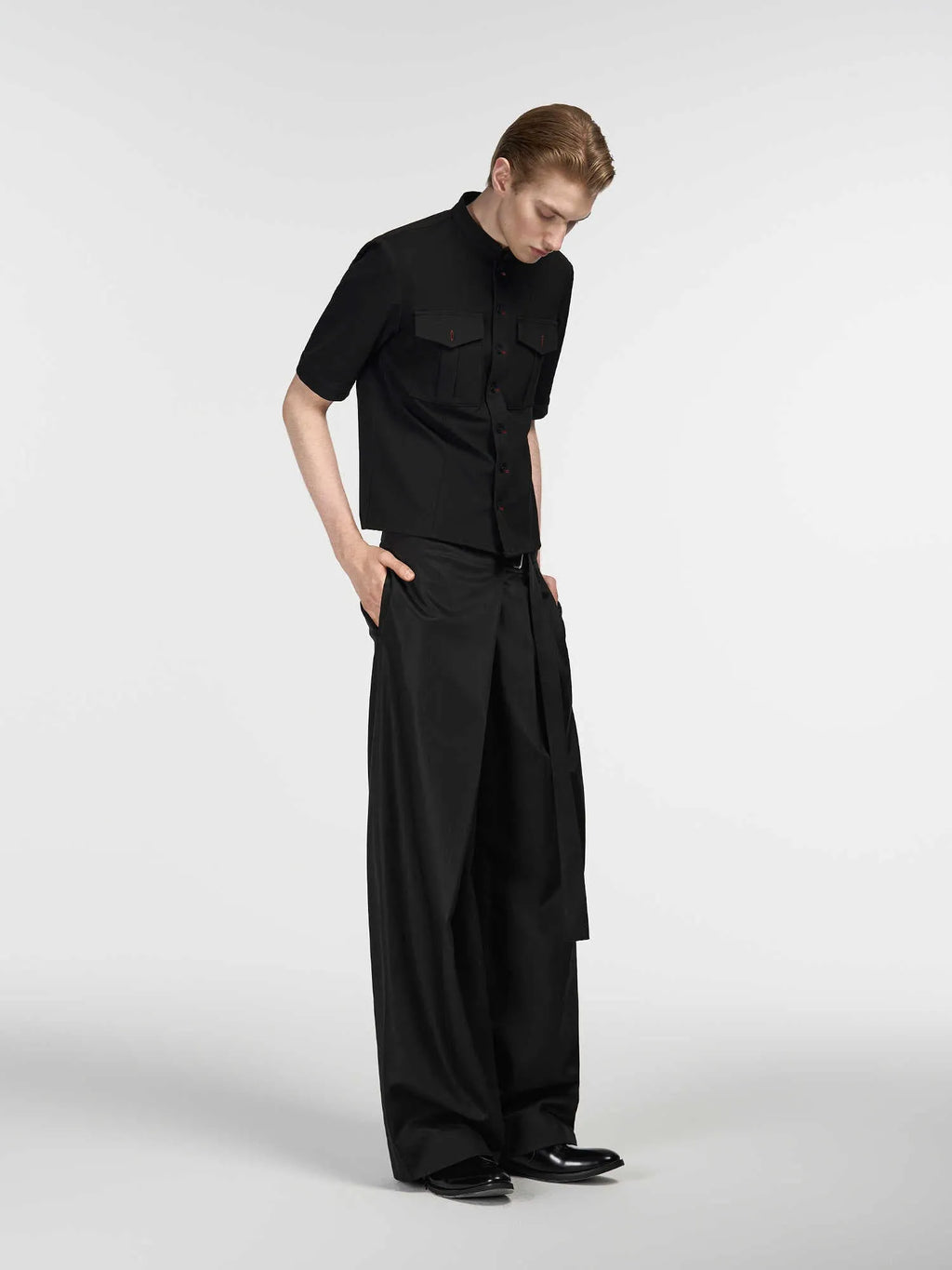 Black straight-leg trousers with adjustable waist and single pleat detail on a hanger.