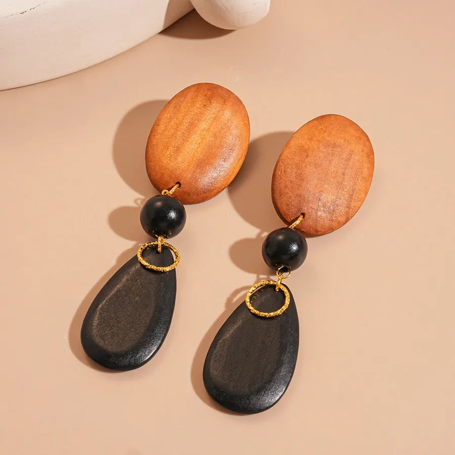 Pair of brown and black wooden retro earrings with an elliptical shape and silver needle detail.
