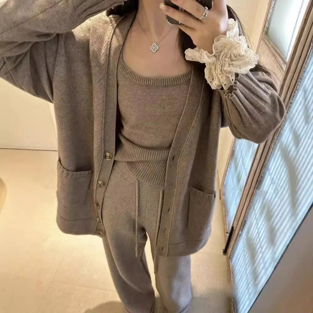 Women's light brown wool blend knit cardigan, vest, and trousers three-piece set laid flat.