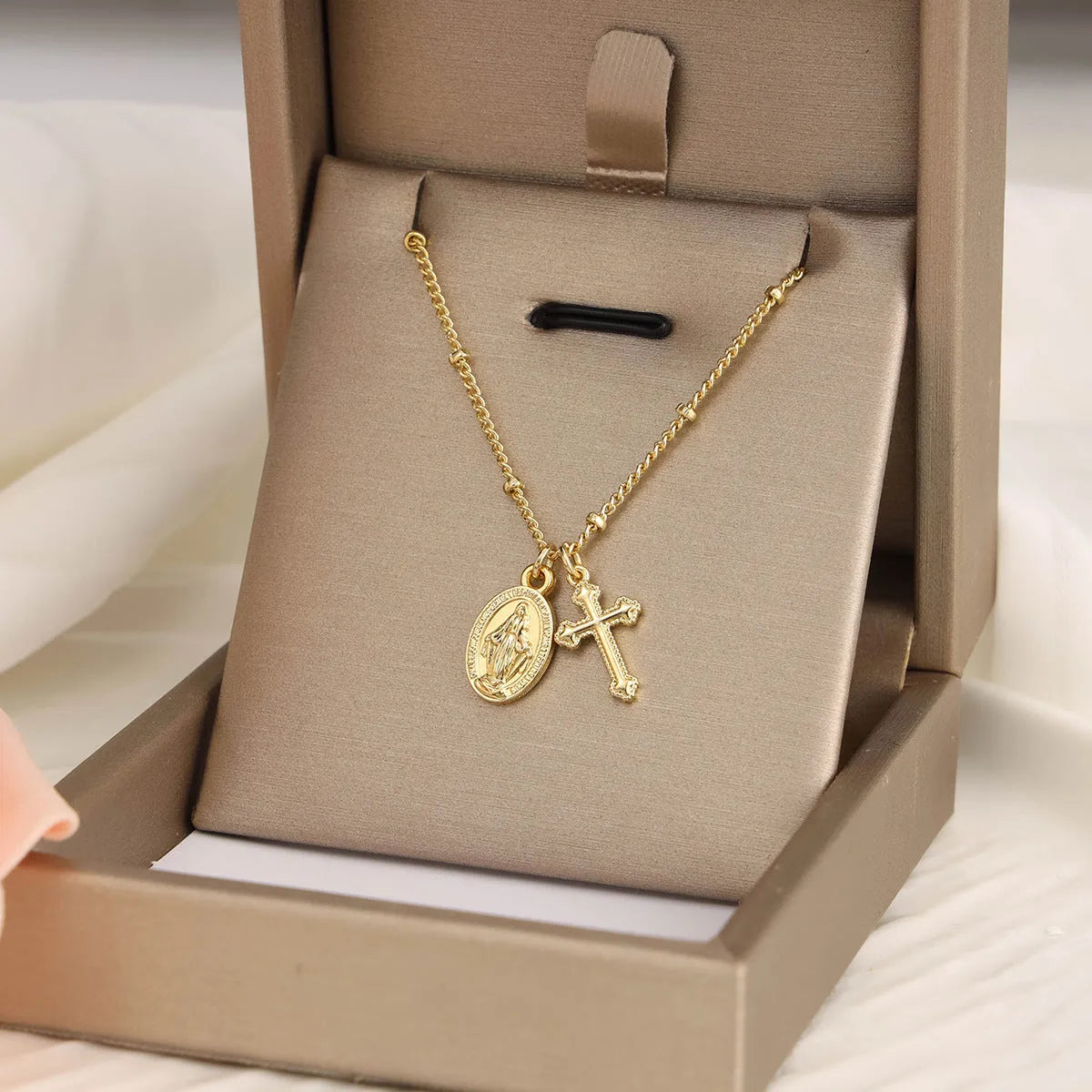 Geometric gold cross Virgin Mary pendant necklace on a chain with a lobster clasp.