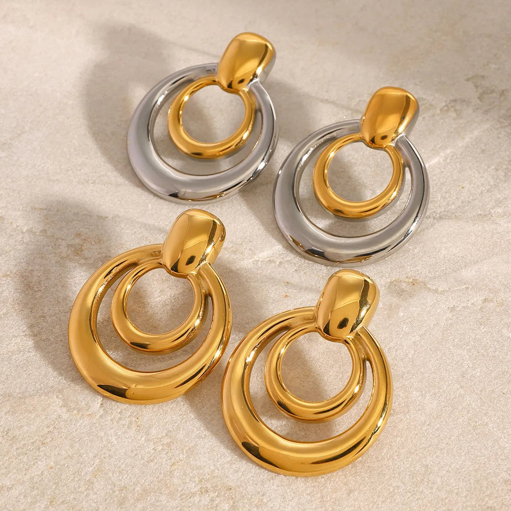 Round golden double layer hollow stud earrings with a geometric design on a white background.