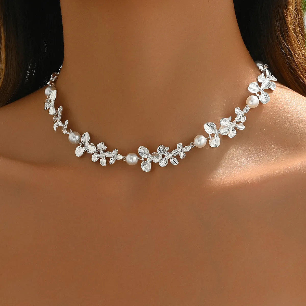 Bright silver alloy flower pearl curved needle clavicle necklace on neutral background