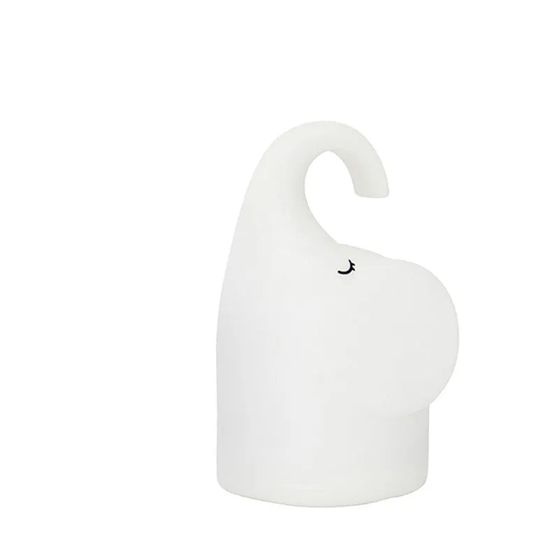 White silicone elephant-shaped night light with a warm glow on a bedside table.