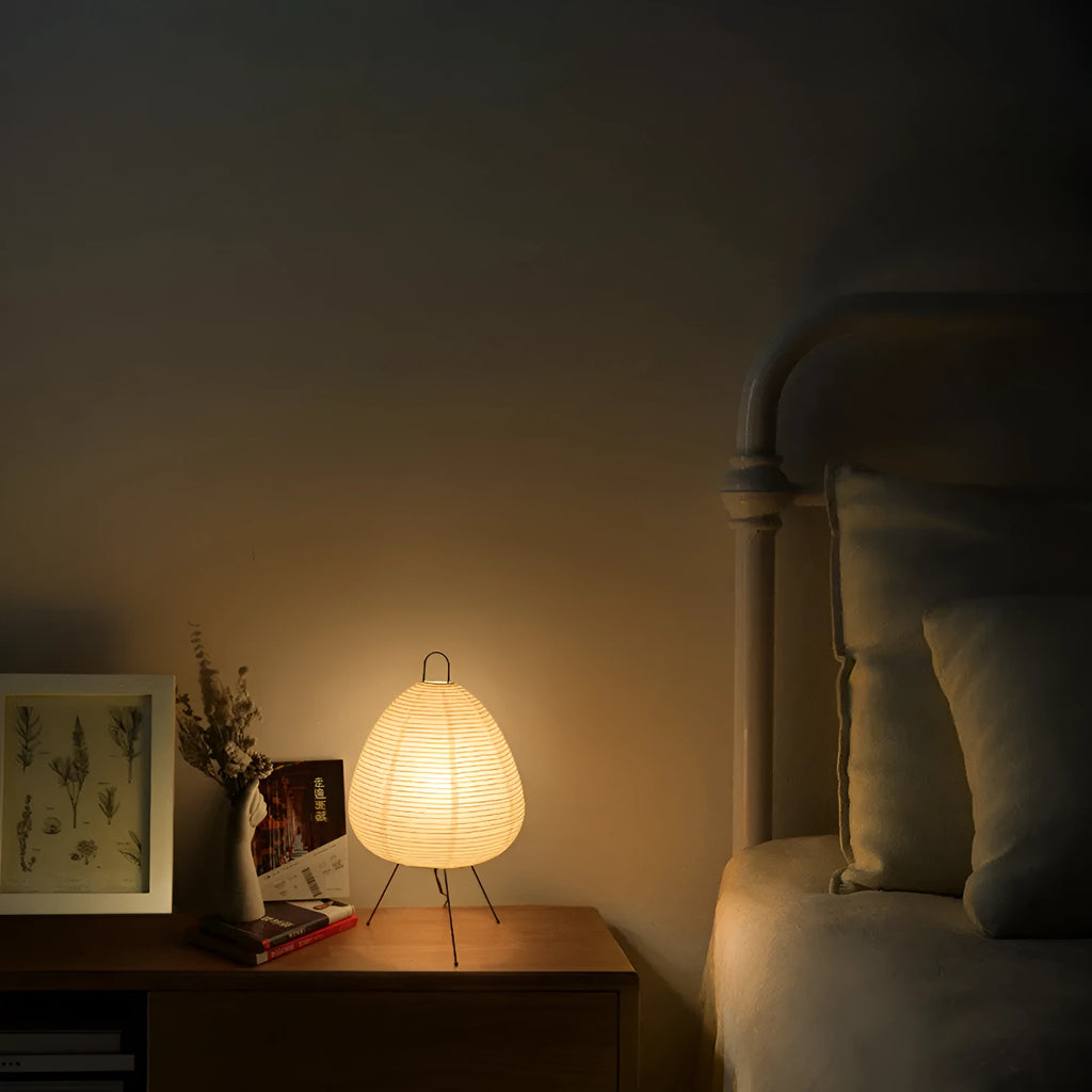 Japanese style table lamp with a white handmade rice paper lantern shade and aluminium base on a wooden table.