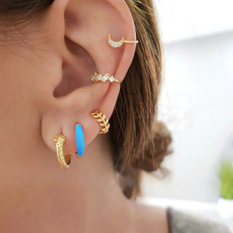 A pair of curved U-shaped epoxy earrings with a translucent blue dripped oil finish and a silver hook on a white background.