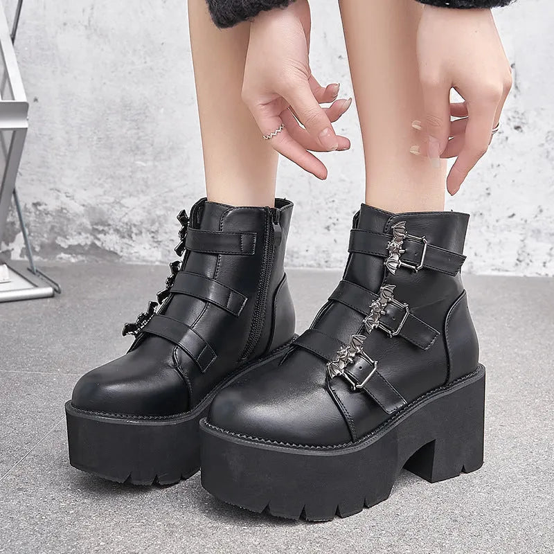 Black women's punk ankle boots with metal bat buckle and thick platform sole.