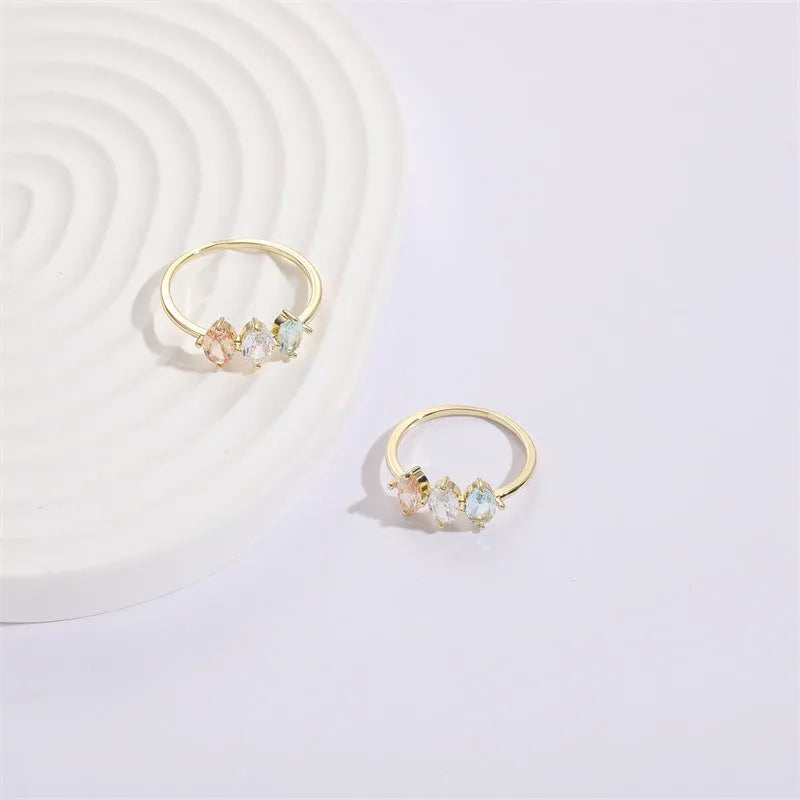 Geometric copper ring with a triangular tricolour zircon birthstone in a horse eye design, showing 14k gold electroplated finish.