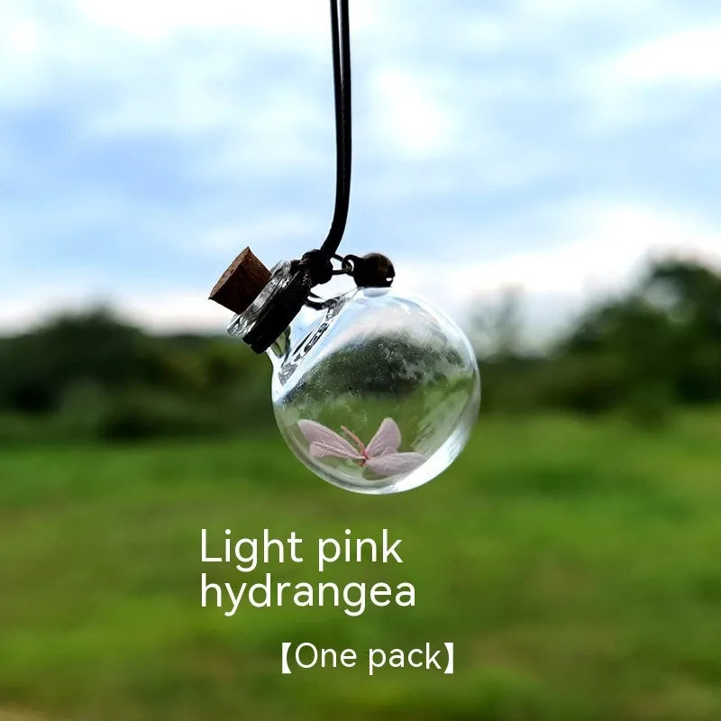 Glass car perfume pendant with preserved flowers inside, shown in a selection of different floral colours.