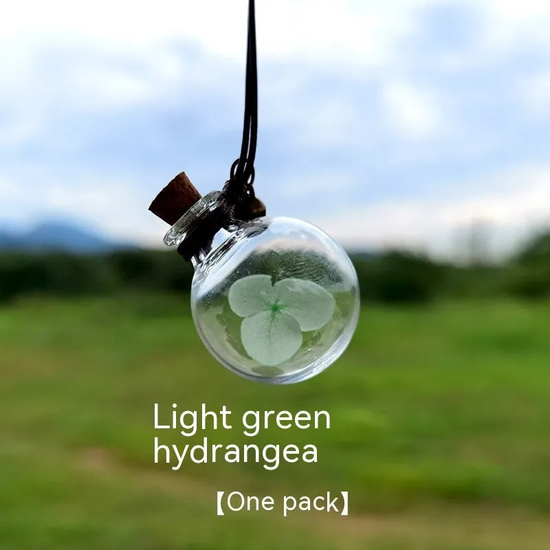 Glass car perfume pendant with preserved flowers inside, shown in a selection of different floral colours.