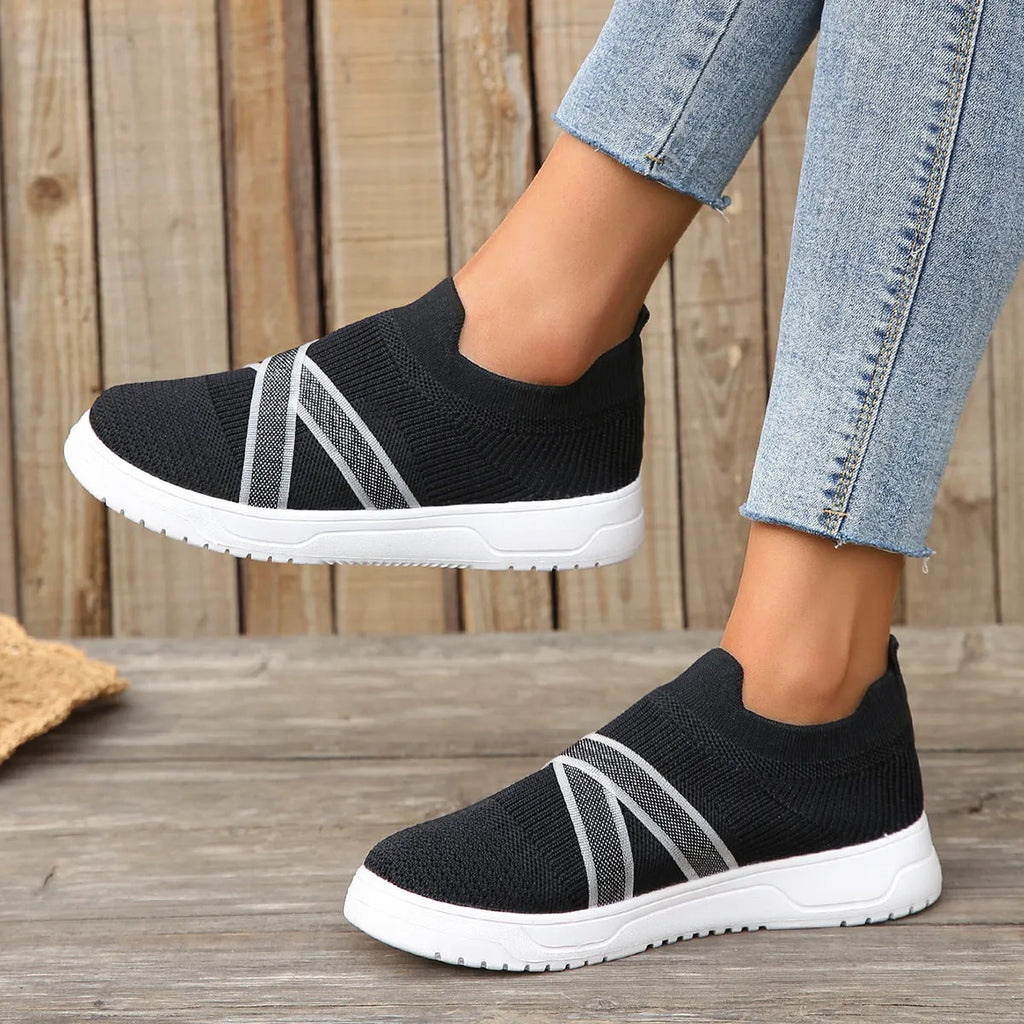 Black women's flat casual shoes with flyknit mesh upper and tassel detail on a flat rubber sole.