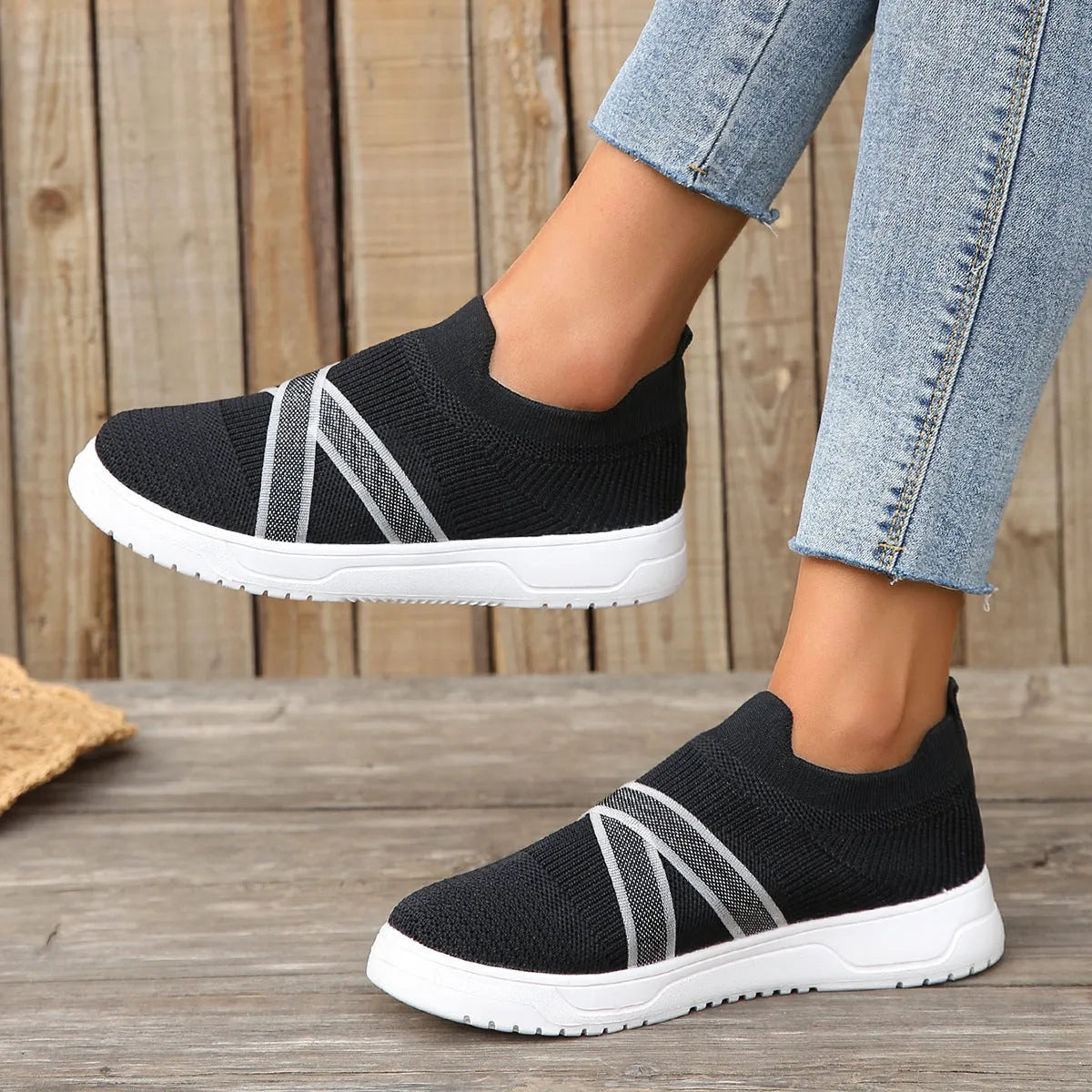 Black women's flat casual shoes with flyknit mesh upper and tassel detail on a flat rubber sole.