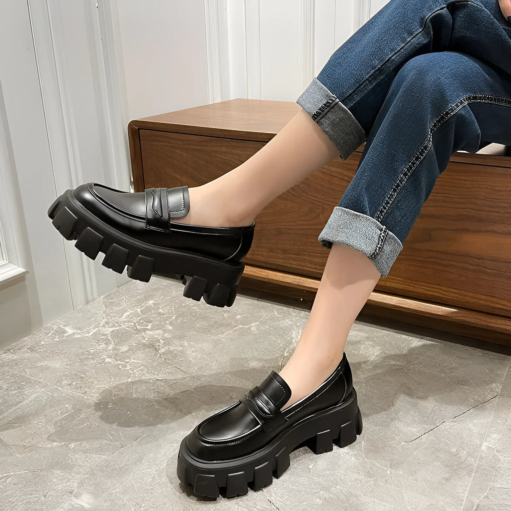 A pair of British style wide fit loafers in either matte or glossy patent leather with a shallow opening and rubber sole.