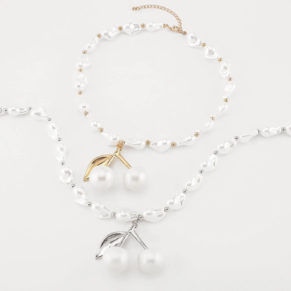 Gold tone irregular necklace with cherry fruit pendant and adjustable string of round pearls on a model
