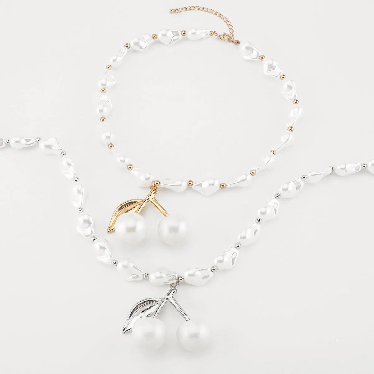 Gold tone irregular necklace with cherry fruit pendant and adjustable string of round pearls on a model