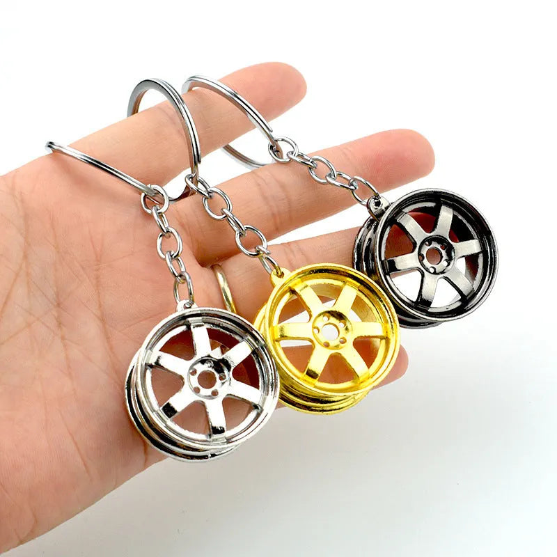 Zinc alloy car wheel hub keychain in gold, silver, and black colour options.