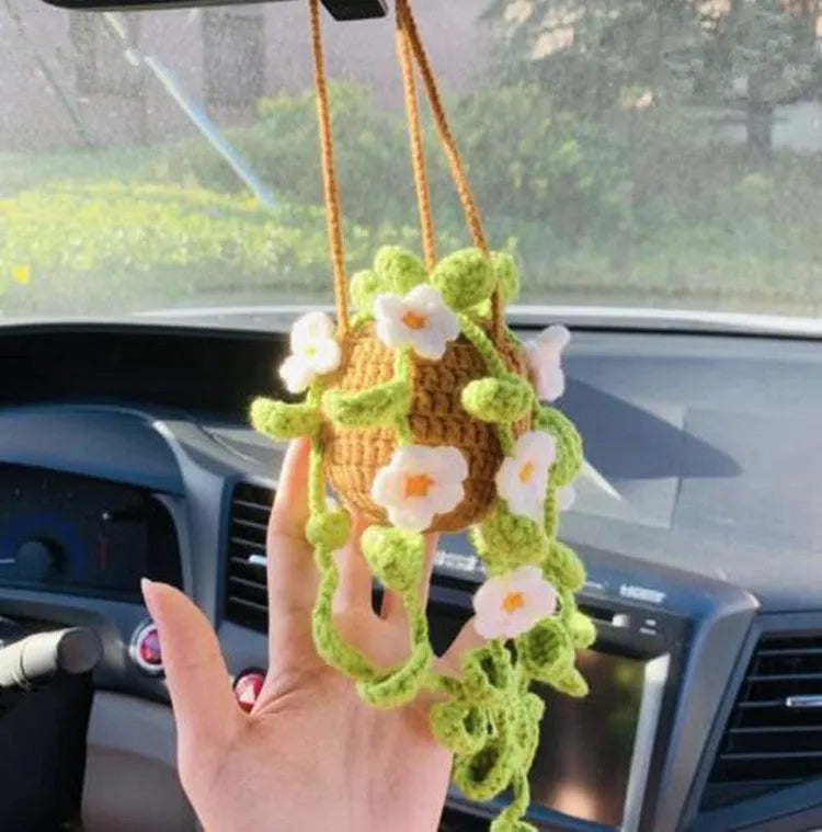 Green and white crocheted wool car plant decoration with a white hanging rope.