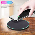 Black circular Qi wireless charging pad for iPhone 11 on a desk.