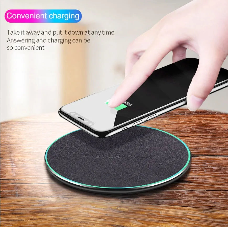 Black circular Qi wireless charging pad for iPhone 11 on a desk.