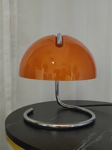 Retro metal mushroom table lamp with three-colour light in orange finish on a bedside table