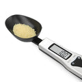 Digital smart measuring spoon with electronic display showing weight, placed on a kitchen worktop.
