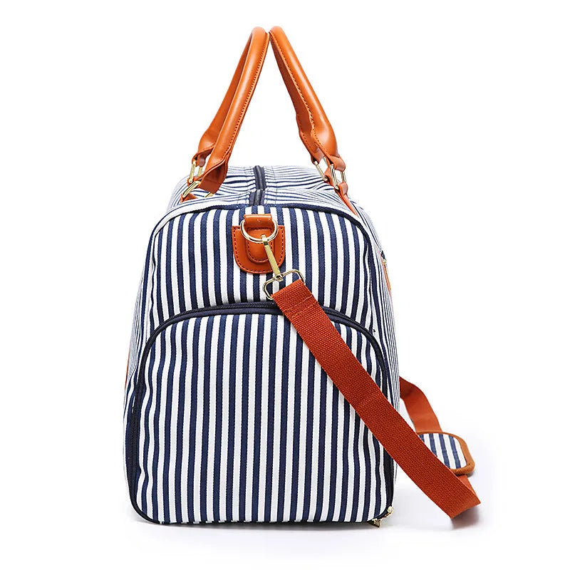 Large striped canvas travel duffel bag with contrast colour and leather detailing, horizontal square shape and zip top.