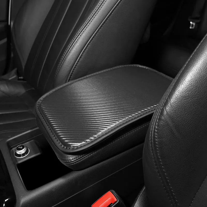 Leather car armrest cushion with carbon fibre pattern in red, shown on a car centre console.