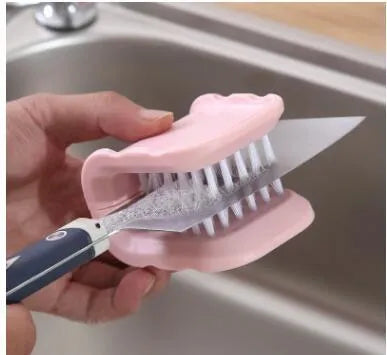 Blue U-shaped plastic brush for cleaning kitchen knives and forks on a draining board.