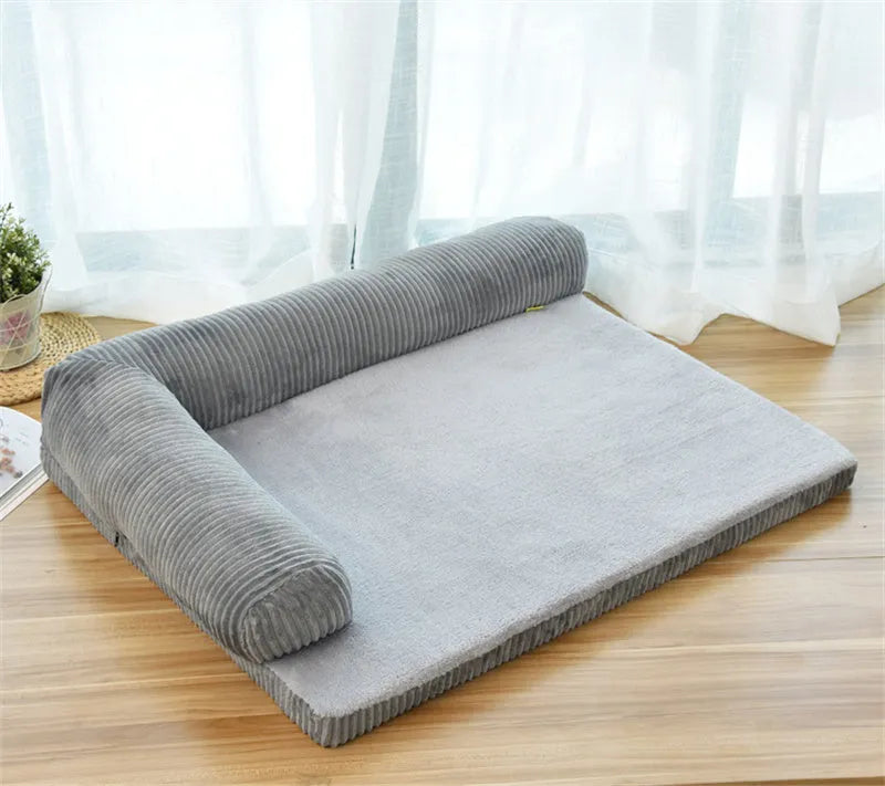 A corduroy dog sofa bed with a raised bolster side, shown in a grey colour on a wooden floor.