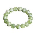 Green milk-in-water Xiuyan jade bracelet with polished geometric beads on a wrist.